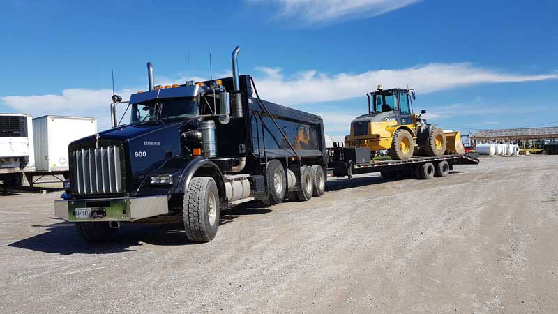 A truck hauling a loader on a flatbed.