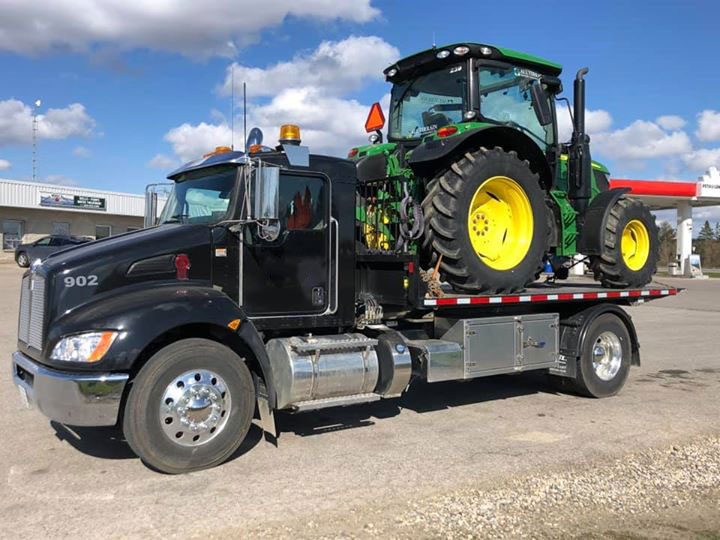 A truck hauling a tractor on a flatbed.